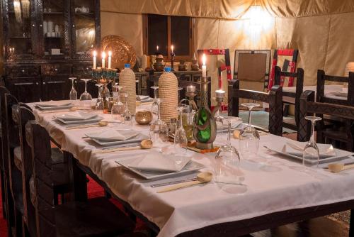 a long table with a white table cloth on it at Dunes Berber Camp in Merzouga