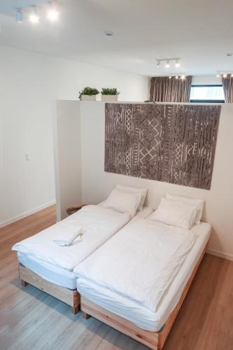 two beds in a room with white walls and wood floors at ApartmentJacob 2 in Antwerp
