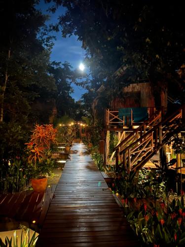 a long wooden walkway in a garden at night at Boatique Hotel and Marina in Rio Dulce