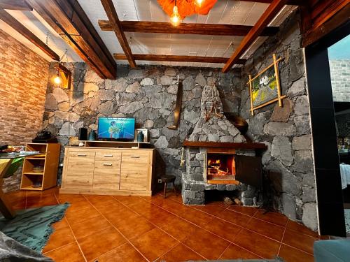 a living room with a stone wall with a fireplace at Casa da Nogueira in Porto Moniz