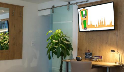 a tv hanging on a wall next to a table with a plant at Ferienwohnung am Griesgarten in Bamberg