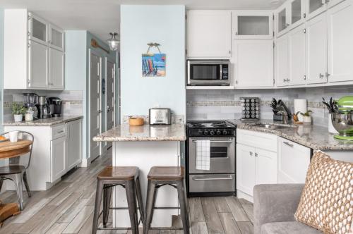 a kitchen with white cabinets and a counter with stools at CDM 303 - Sandy Seashore Solace in Galveston