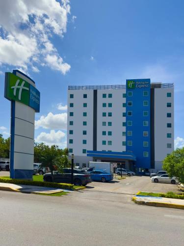 a building with a sign in front of a parking lot at Holiday Inn Express Mérida by IHG in Mérida