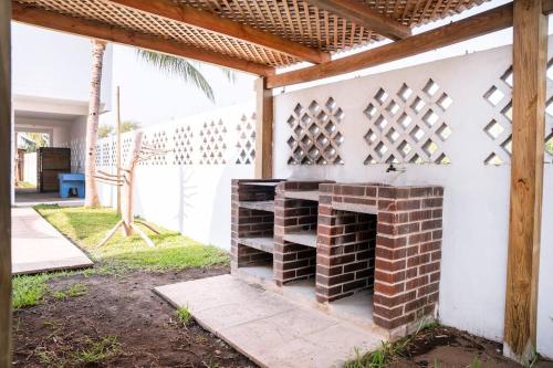 a brick fireplace in a backyard with a pergola at Playa Monterrico, Candelaria2 in Taxisco