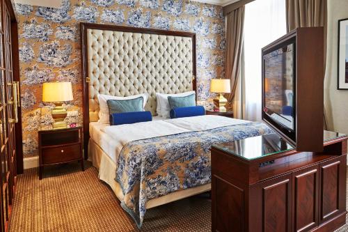 a bedroom with a large bed and a television at Steigenberger Icon Frankfurter Hof in Frankfurt/Main