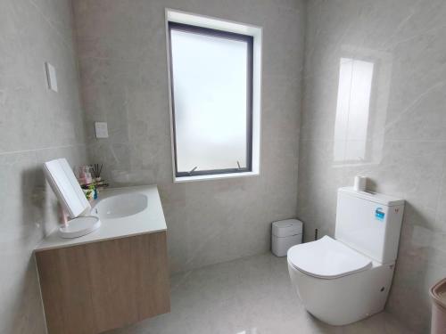 a bathroom with a toilet and a sink and a window at Orewa New house with view on deck near Cafe,bush & river in Orewa
