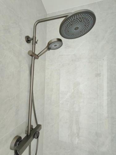 a shower with a shower head in a bathroom at Orewa New house with view on deck near Cafe,bush & river in Orewa