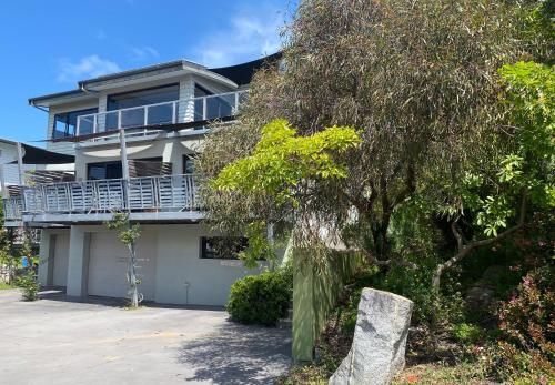 a white house with a balcony and a tree at Saltair Luxury Accommodation - Adults Only in Albany