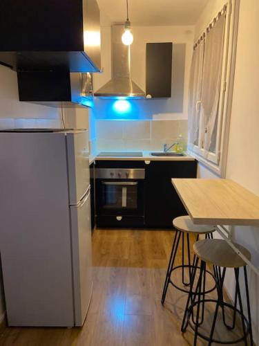 une cuisine avec un réfrigérateur et une table avec des tabourets dans l'établissement Charmant Appartement à Tours, à Tours
