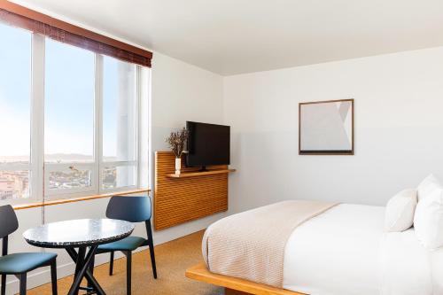 a bedroom with a bed and a table and a tv at Hotel June West LA, a Member of Design Hotels in Los Angeles