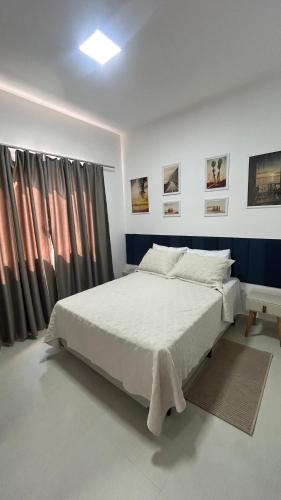 a bedroom with a white bed and some curtains at Apartamento Terra Firme in Rio das Ostras