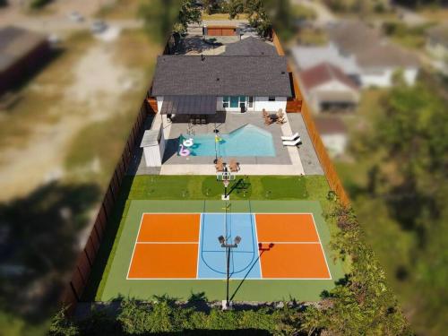 an overhead view of a house with a tennis court at Pickleball Paradise Retreat - 4 Bedrooms, 2,5 Baths - Houston Downtown, Houston Heights - Pickleball and Basketball Court, Pool, miniGolf, Karaoke, Fire Pit, BBQ, Billiards, Ping Pong, Hockey, King Bed in Houston