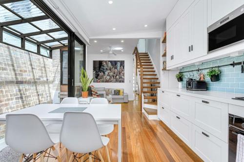a kitchen with a white table and white chairs at The Newtown Nest - Managed by X Hospitality in Sydney
