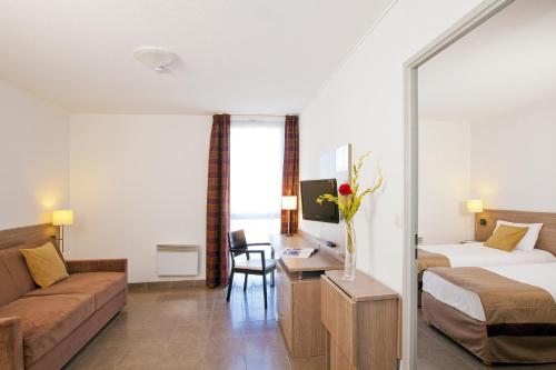 マノスクにあるApparthotel Séjours & Affaires Manosqueのベッドとソファ付きのホテルルーム