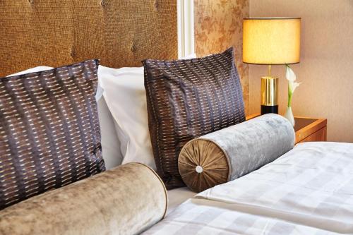 a bedroom with a bed with two pillows and a lamp at Steigenberger Icon Frankfurter Hof in Frankfurt/Main