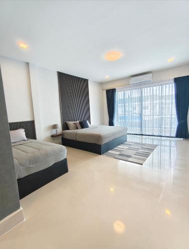 a bedroom with two beds and a large window at Chani House Hatyai in Hat Yai