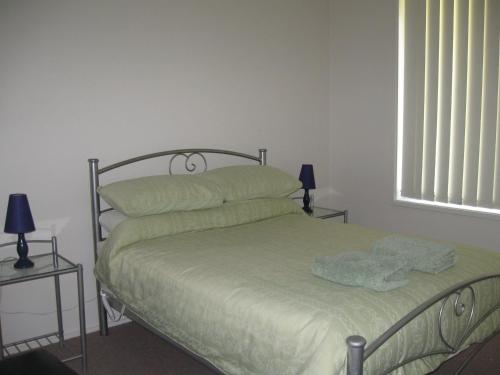 a bedroom with a bed with green sheets and a window at Hayden House in Delegate