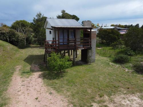 uma pequena casa com um alpendre numa estrada de terra batida em Bahía em Punta Del Diablo