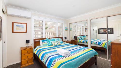 a bedroom with two beds and a mirror at Chill Out at Fingal Jellicoe Close in Fingal Bay