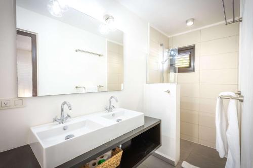 a white bathroom with a sink and a mirror at Indigo Garden at Blue Bay Golf & Beach Resort in Willemstad