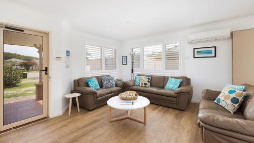 a living room with couches and a table at Chill Out at Fingal Jellicoe Close in Fingal Bay