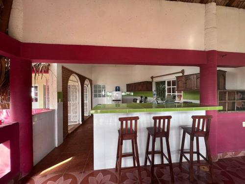eine Küche mit drei Barhockern in einem Haus in der Unterkunft Departamento 4 personas Xela in San Pedro Pochutla