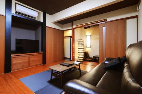a living room with a couch and a tv at 徳の宿 ふぶ庵 in Beppu