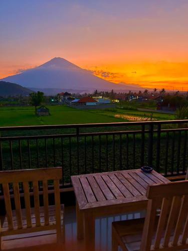 a table and chairs on a balcony with a mountain at D'uma Amed Homestay in Amed