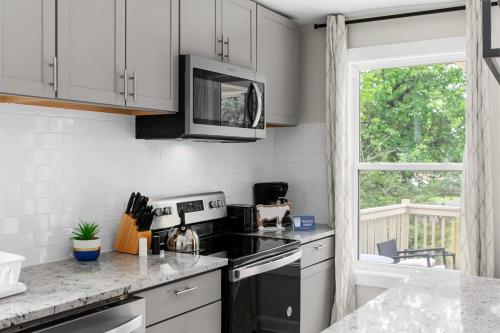 a kitchen with white cabinets and a stove and a window at 10 Mins to Downtown Modern in Magic City- Unit A in Birmingham