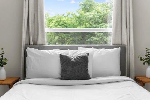a bed with white pillows in front of a window at 10 Mins to Downtown Modern in Magic City- Unit A in Birmingham