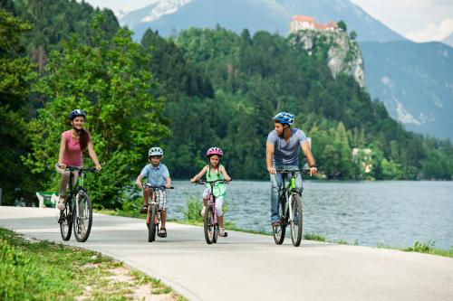 
people riding bikes down a road next to a river at Garni Hotel Savica - Sava Hotels & Resorts in Bled
