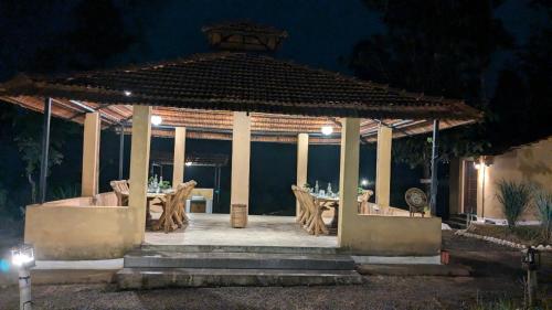 a gazebo with a table and chairs at night at Athulyam Kanha, kanha national park, mukki gate in Khāpa