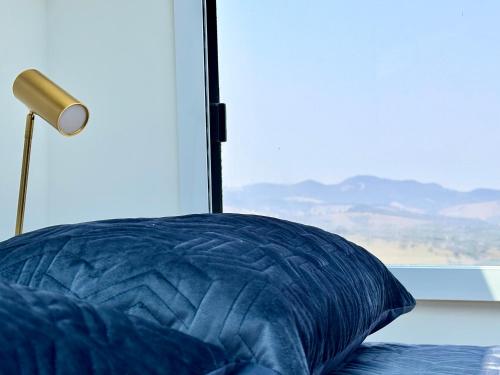 a bed with a blue pillow next to a window at Refúgio estelar com vista para represa in Joanópolis