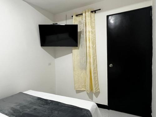 a bedroom with a black door and a television at Hogar El Descanso Itagui in Itagüí