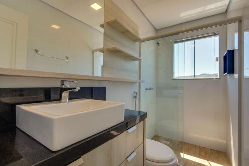 フロリアノポリスにあるImigrantes Apart Hotelの白い洗面台とトイレのあるバスルーム