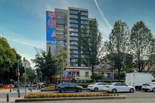 a parking lot with cars parked in front of a tall building at Myla Roma Norte in Mexico City