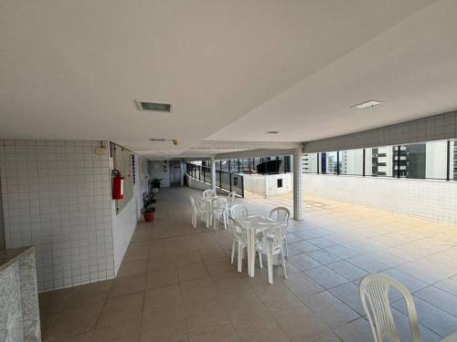 a room with white chairs and tables in a building at Flat Rosarinho - Confortável e Super Completo in Recife