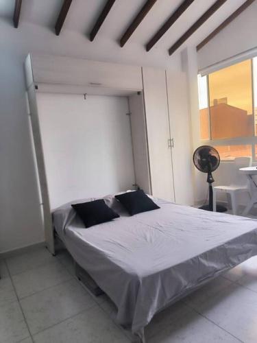 a bed in a white room with a large window at Apartaestudio completo en Itagüí - Ágape in Itagüí