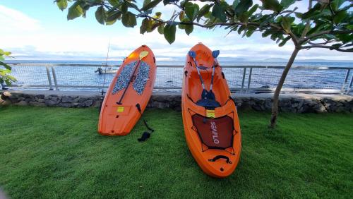 two orange kayaks sitting on the grass near the water at Lacus De Gracia in Batangas City