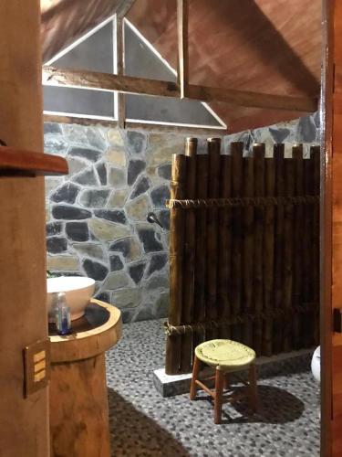 a room with a stone wall and a table and a stool at Jardín Secreto Bungalows in Aquismón