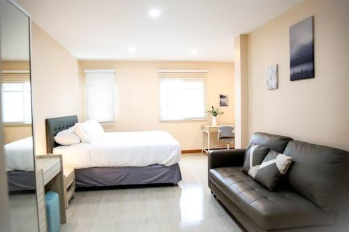 ein kleines Schlafzimmer mit einem Bett und einer Couch in der Unterkunft Near BTS Bearing Skytrain- Homey living Townhome - 4 Bedrooms in Bangkok