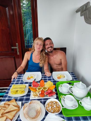 a man and woman sitting at a table with food at Green nature in Mirissa