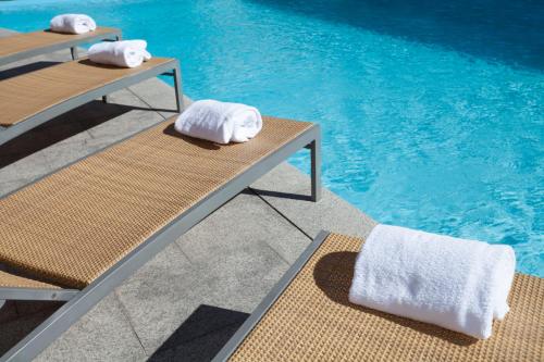 two towels sitting on benches next to a swimming pool at Novotel Konya in Konya