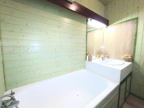une salle de bain avec une baignoire, un lavabo et un miroir dans l'établissement Studio cosy à Plagne Centre, à 100m des pistes, avec balcon - FR-1-351-239, à La Plagne Tarentaise