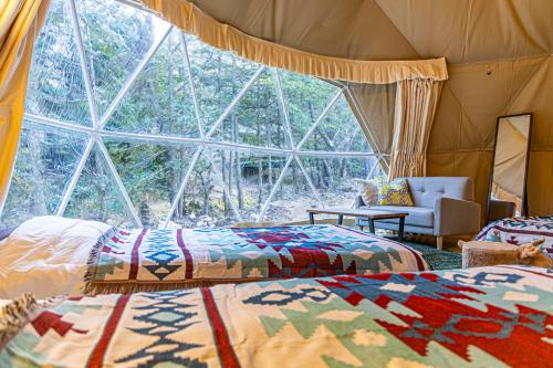 a room with two beds and a large window at glampark Hinokiyunoyado Nagano in Azumino