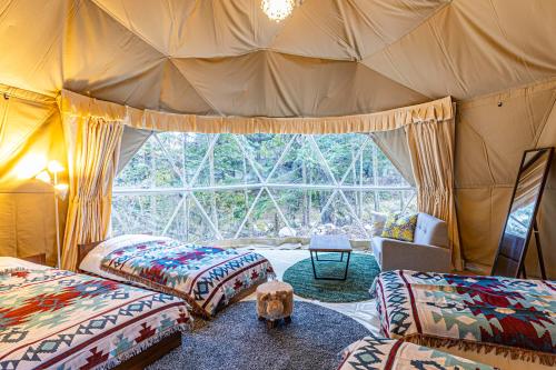 a room with three beds and a large window at glampark Hinokiyunoyado Nagano in Azumino