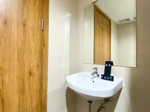 une salle de bain avec un lavabo et un miroir dans l'établissement Well Furnished and Cozy Studio at Gateway Park LRT City Jatibening Apartment By Travelio, à Bekasi