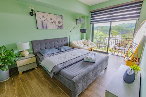 a bedroom with a bed and a couch and a balcony at Green House - Căn hộ có bếp riêng in Da Lat