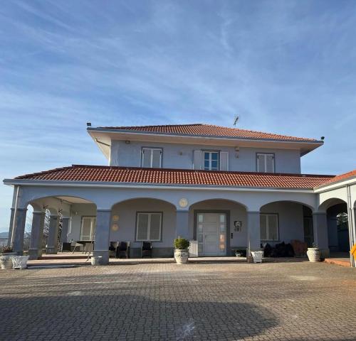 a large white house with a red roof at Splendid Villa Magna with Pool and Park - Langhe Hills in Govone