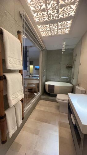 a bathroom with a tub and a toilet and a sink at Sojourn Spa Hotel Melaka in Melaka
